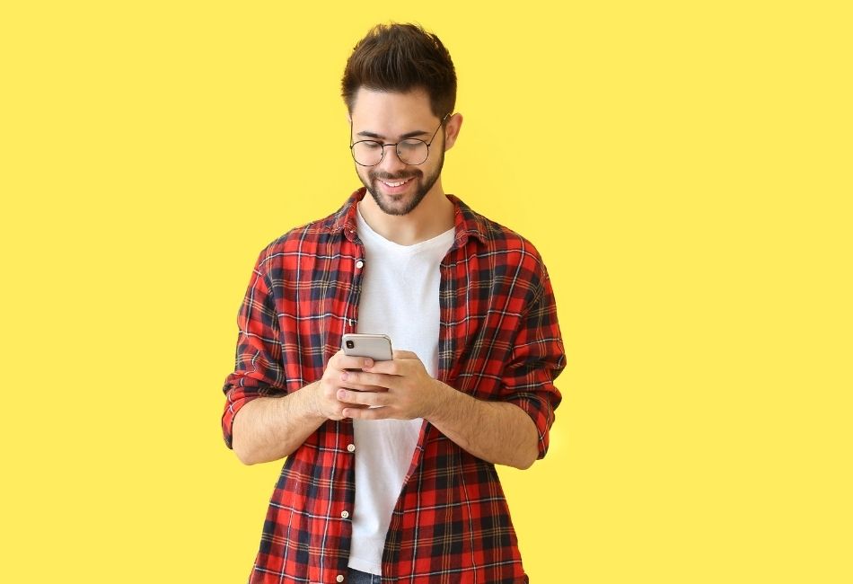 Creator checking his phone against a yellow background